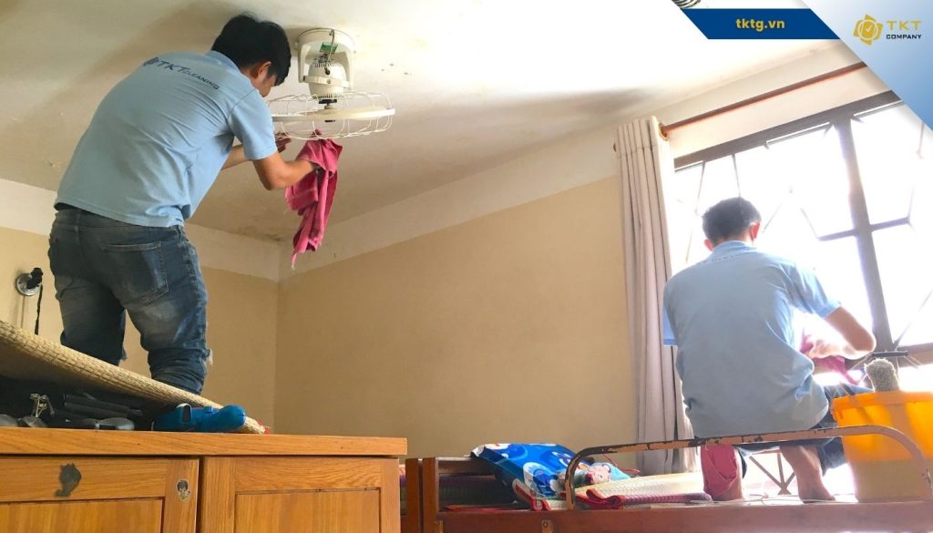 Hai nhân viên dịch vụ vệ sinh nhà ở lau trần và sàn trong căn nhà