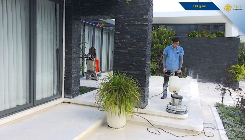 Nhân viên dịch vụ vệ sinh nhà ở dùng máy chà sàn trước hiên nhà phố