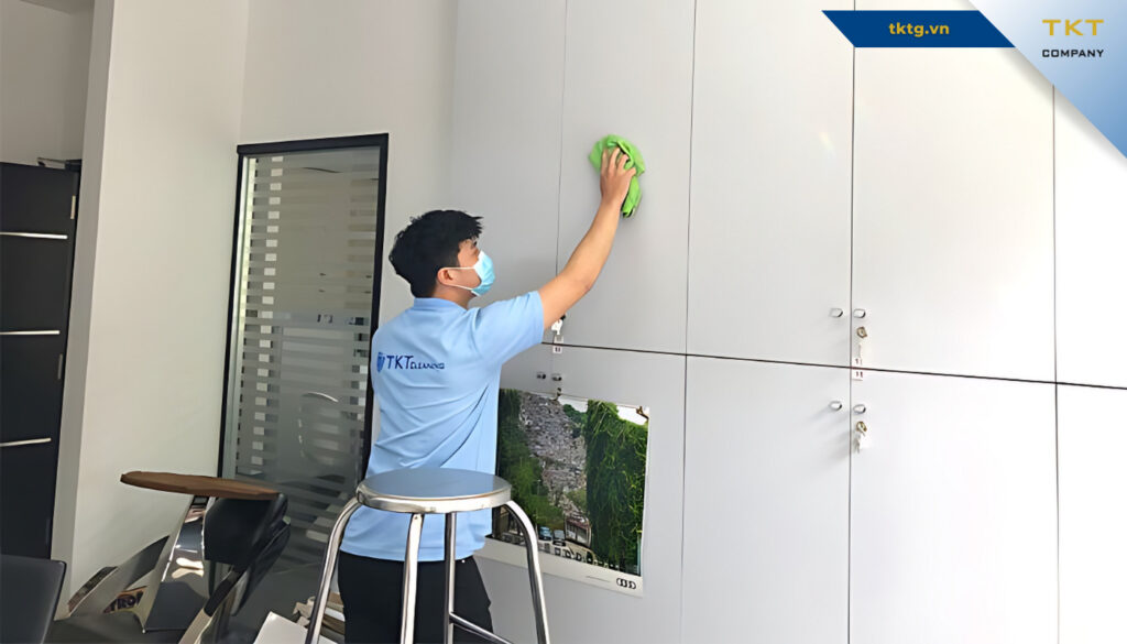 Nhân viên trên thang lau mảng tường và kính trong tầm với