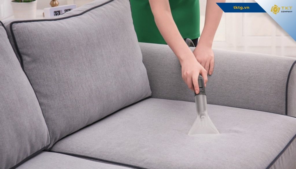 Kỹ thuật viên phun hút làm sạch ghế sofa vải trong dịch vụ giặt ghế sofa

