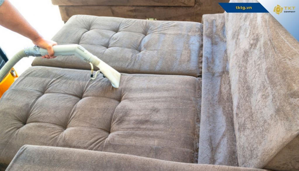 Kỹ thuật viên làm sạch ghế sofa nhung bằng đầu hút chuyên dụng