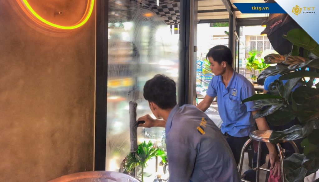 Nhân viên TKT Company lau kính mặt trong mặt tiền bằng gạt kính chuyên dụng