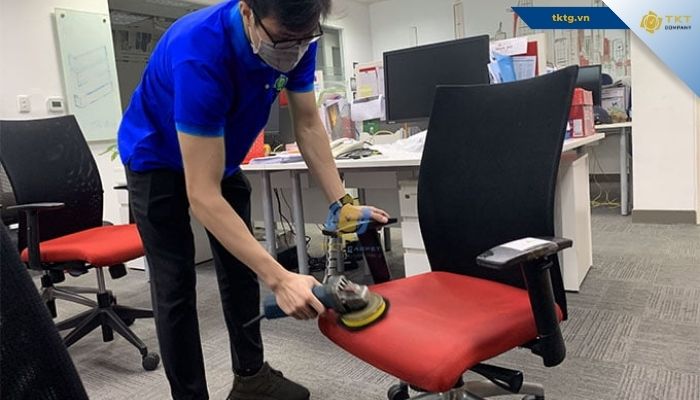 Nhân viên TKT Company chà mặt nệm ghế văn phòng bằng bàn chải chuyên dụng