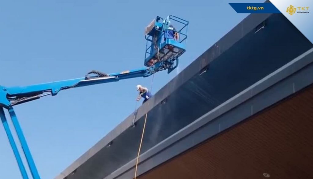 TKT Company kết hợp xe nâng người và dây đu để vệ sinh mặt dựng nhà cao tầng