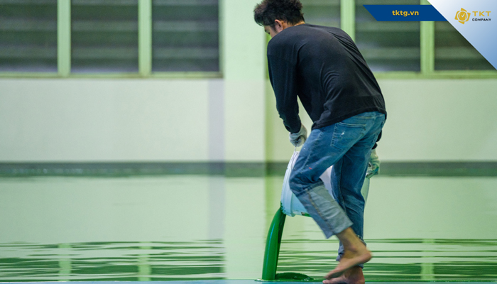 Thợ kéo lớp sơn epoxy phủ đều mặt nền trong nhà xưởng